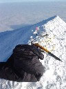 The GPS, wrapped in Damien's black jumper, on the summit. The round white antenna is next to the little red summit marker and the orange ice axe is to stop it all falling off. At this point the temp was about -30 degrees Celsius. &copy; Geoscience Australia.