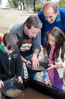 Geoscience Australia staff member gold panning with Open Day visitors.