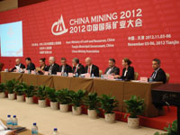 Ten people sitting in a row at a table on stage.