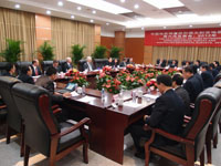 A meeting room with a large number of delegates sitting around a rectangular table.