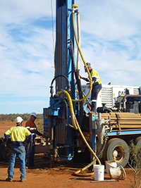 A large drill, approximately 5 metres tall on the back flat-bed truck.