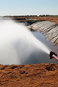 This photo shows water and steam flowing from piping connected to the Paralana 2 well head into a plastic-lined pit dam on Petratherm's Paralana project site, South Australia. Over a seven day period, approximately 1.6 million litres of water was produced at a maximum temperature of 171 degrees celsius.