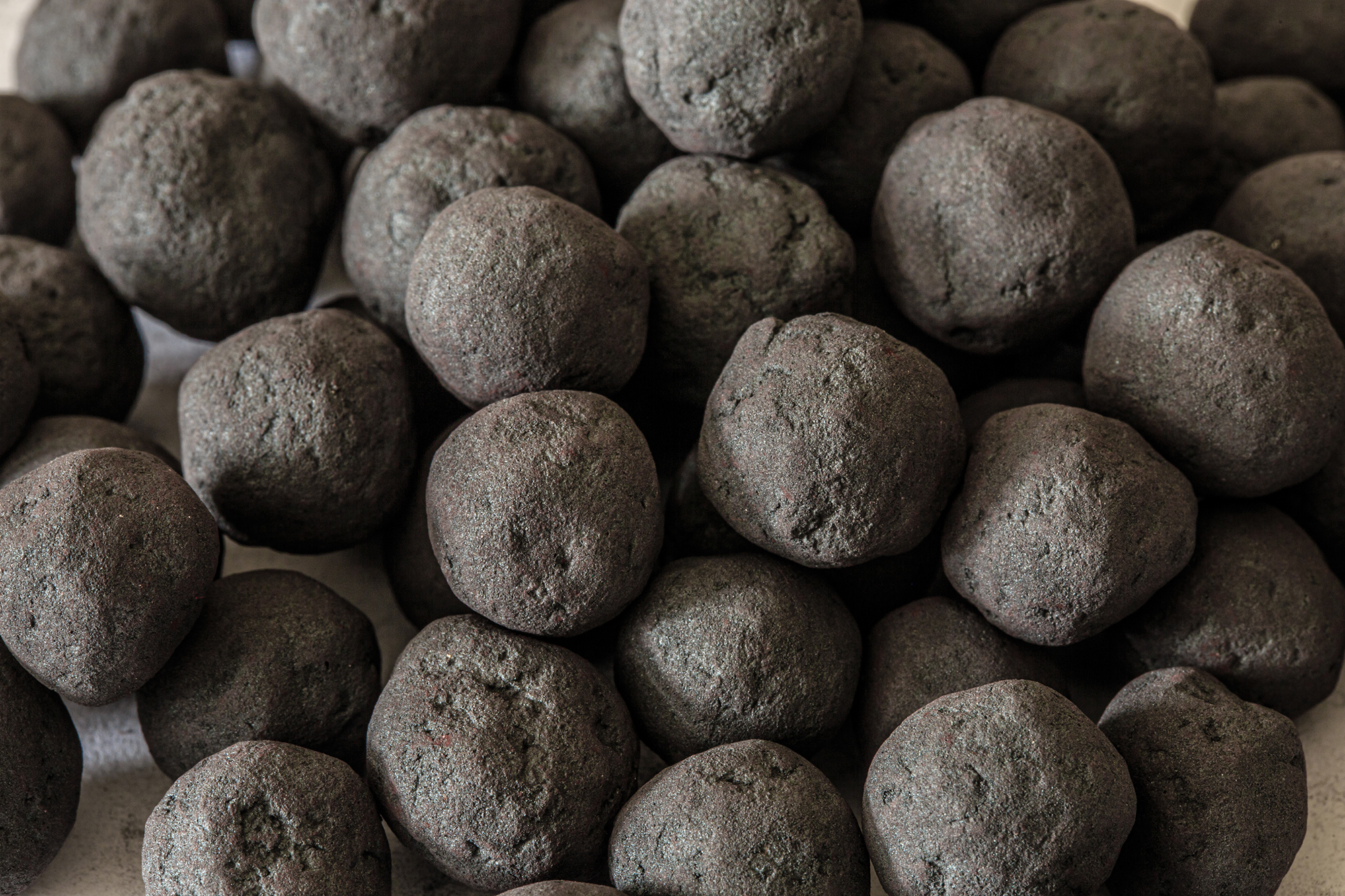 Numerous large spherical iron ore pellets used in steel production.