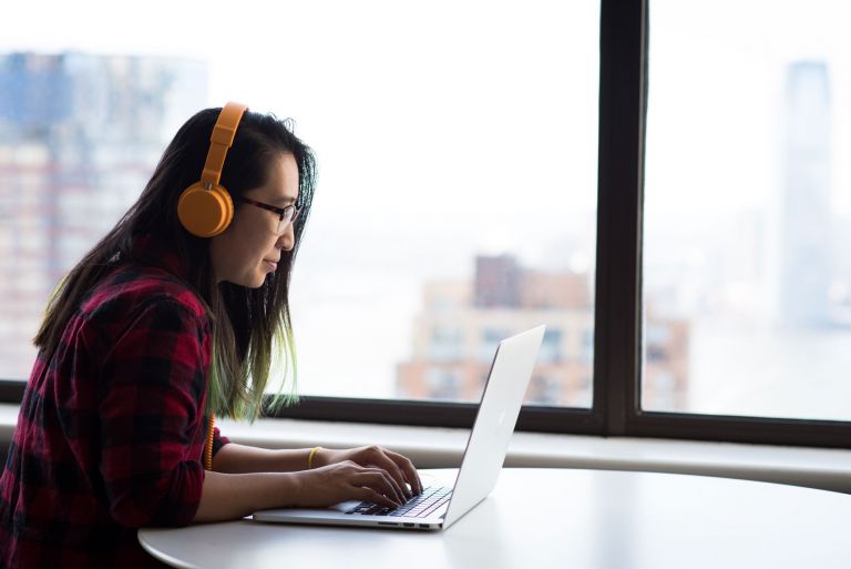 Woman wearing headphones and using laptop