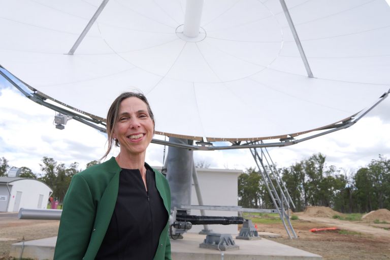 Dr Martine Woolf from Geoscience Australia standing in front of a satellite