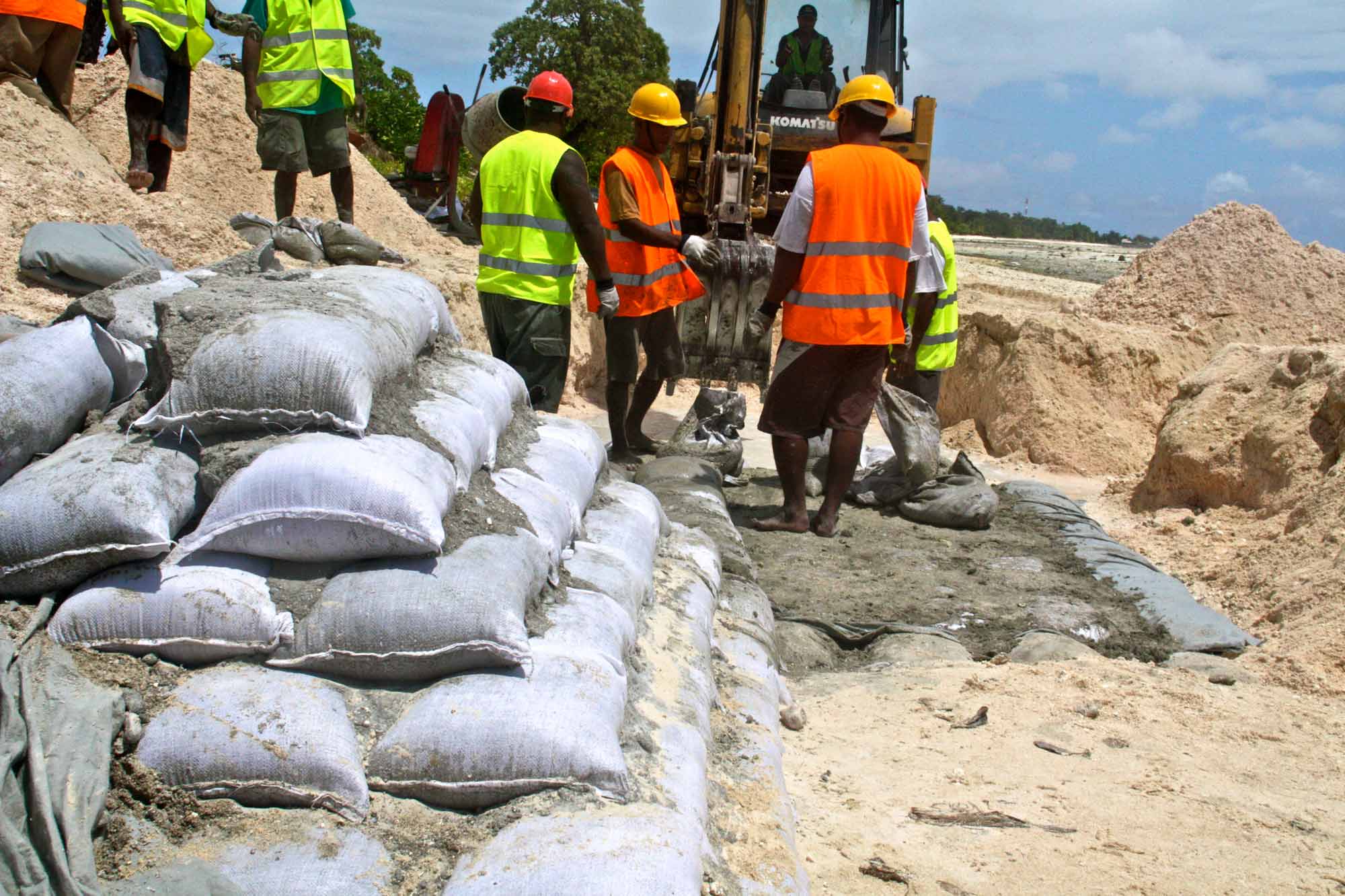 Workers construct a coastal protection barrier using sandbags as part of a flood mitigation project in Kiribati