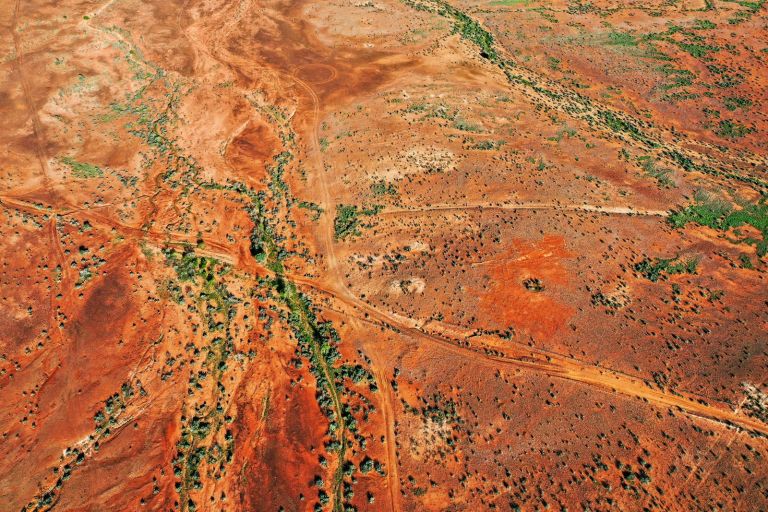 Outback rural landscape with red earth, dry rivers and green trees, Australia, aerial view
