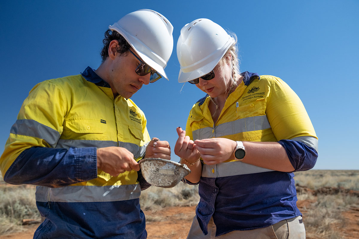 Two geoscientists, one male, one female - wearing yellow high visibility shirts