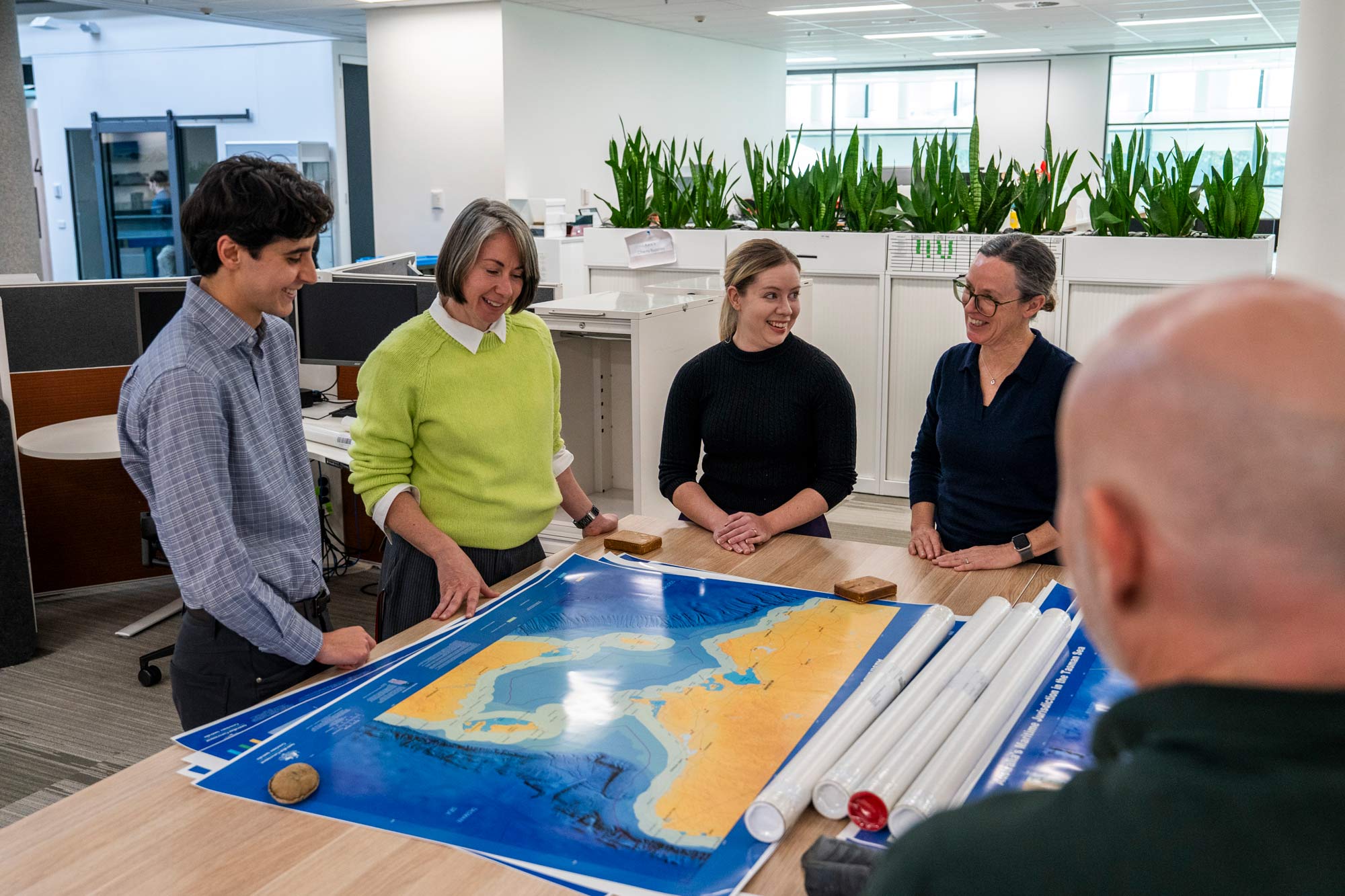 Geoscience Australia staff reviewing a large printed marine map during a collaborative planning session