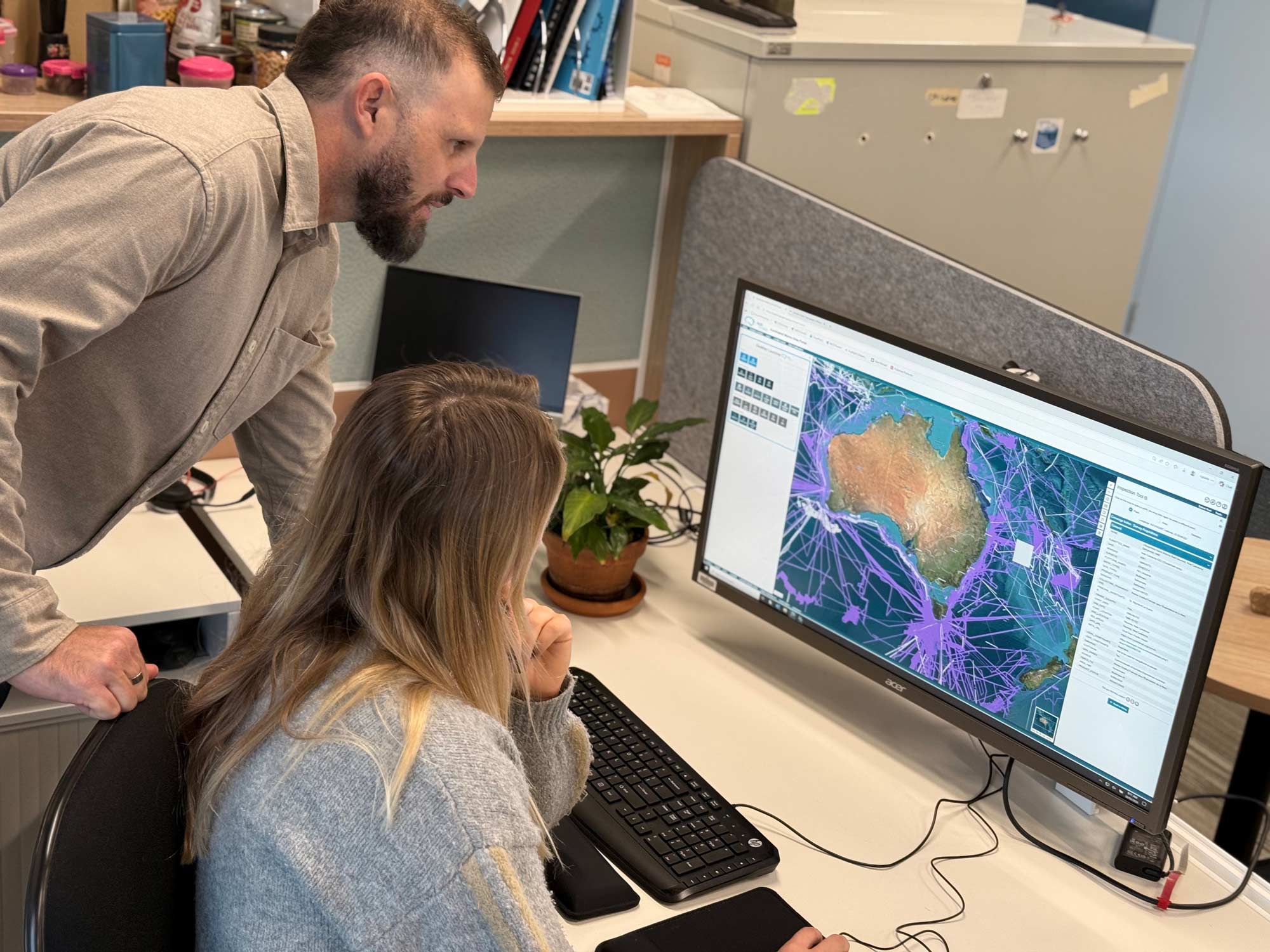 Two Geoscience Australia staff viewing Australia's AusSeabed Marine Data Portal on a computer screen