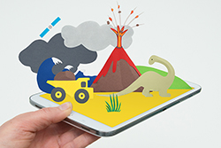 An image of a mobile tablet device with cardboard diorama images of a volcano, truck, dinosaur and tsunami wave.