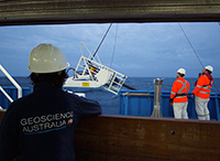 Geoscience Australia researcher watches RV Investigator crew members deploy equipment during a marine geoscience voyage.