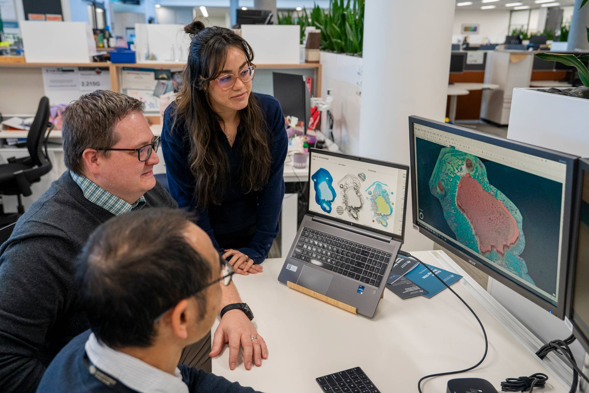 Geoscience Australia staff examining three-dimensional seabed mapping and marine geospatial data on computer displays