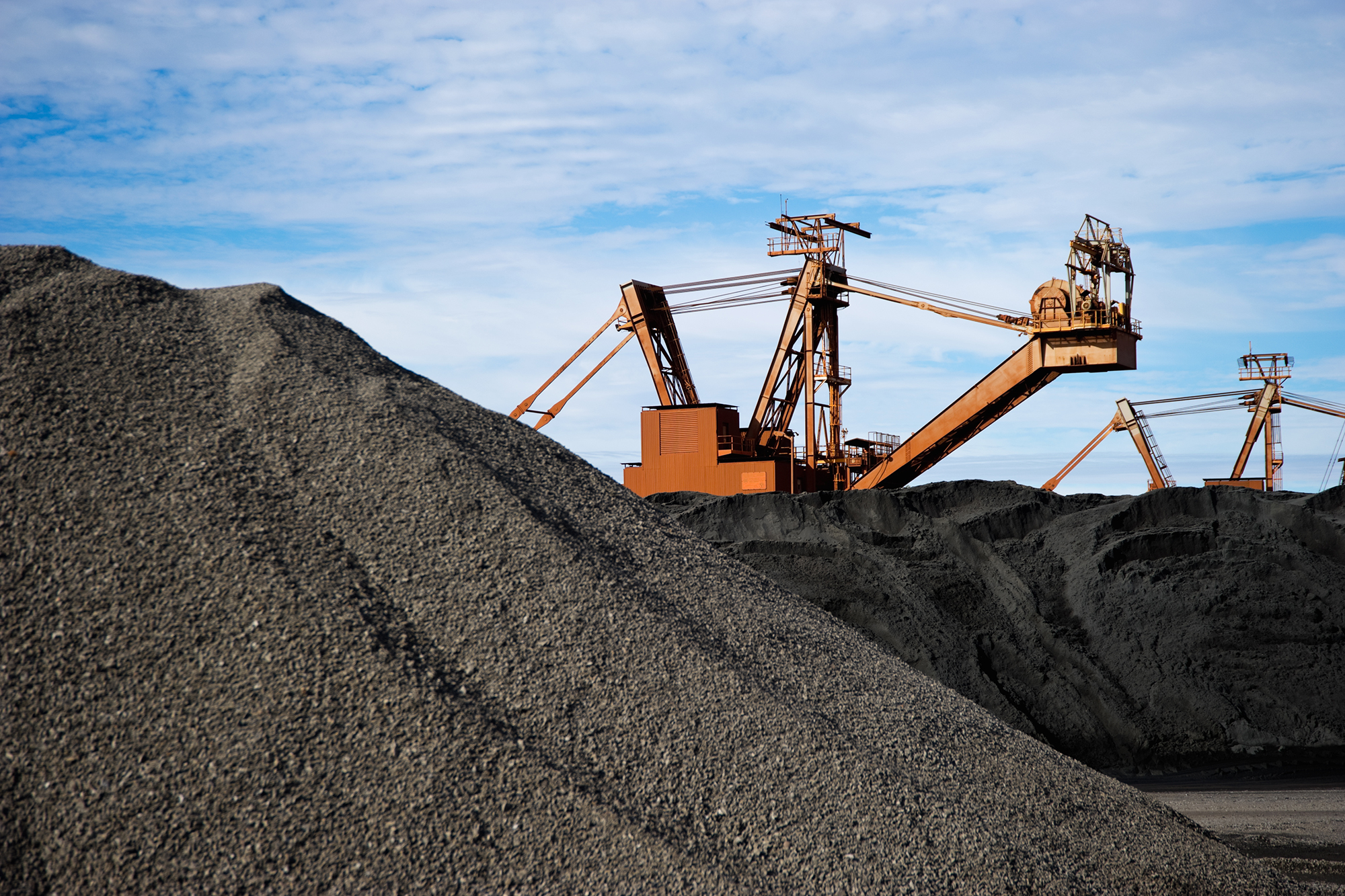 Manganese ore in stockpile at harbor loading site in Port Hedland, Pilbara, Western Australia.cReclaimer and stacker