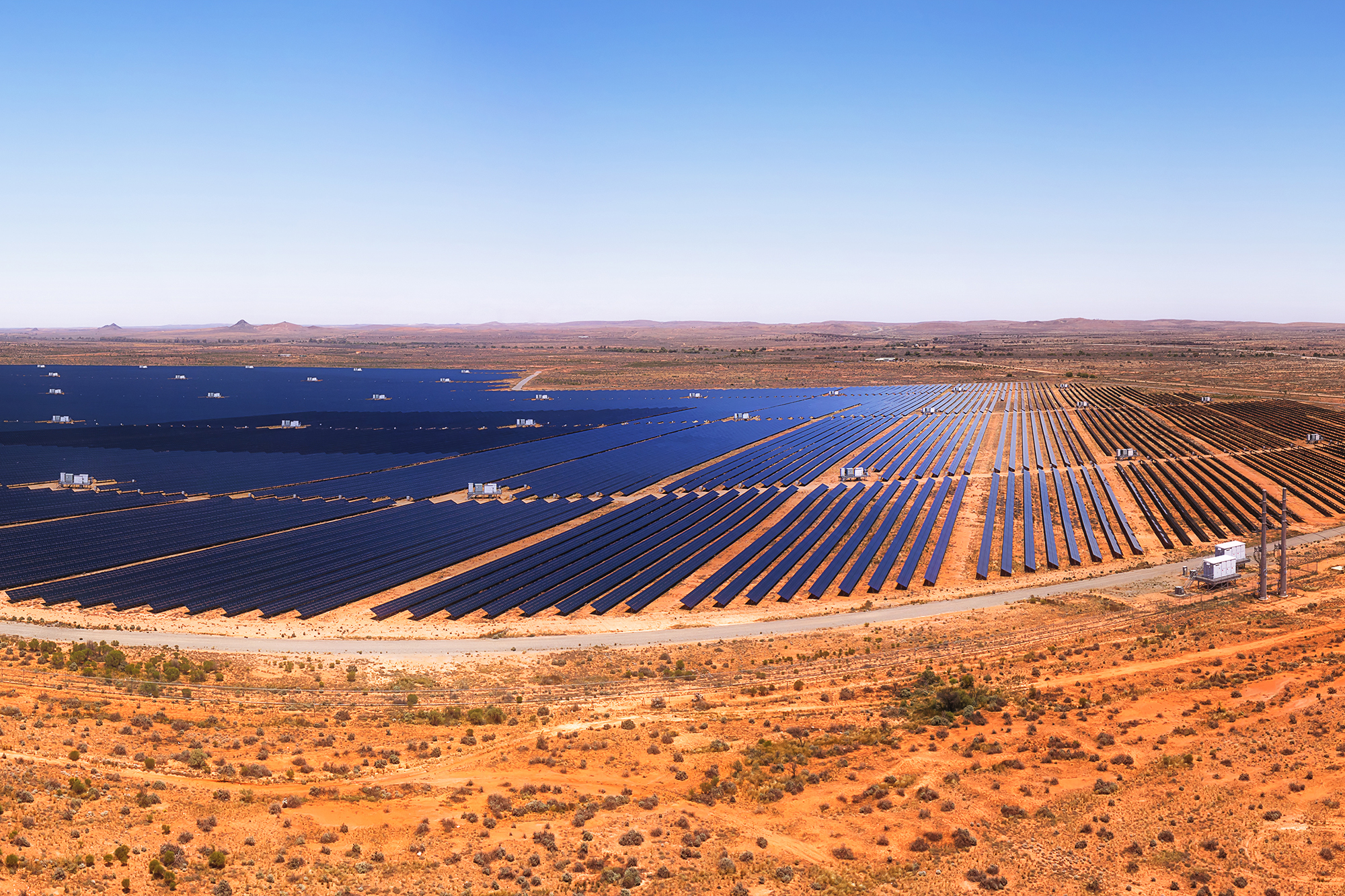 Massive solar power generation plant with solar panels on red soil of Australian outback at Broken HIll city in aerial panorama.