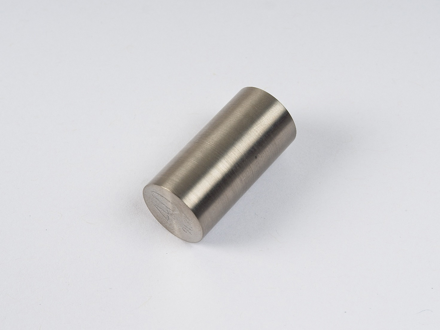 A shiny, silver-coloured, metallic, cylindrical sample of Zirconium.