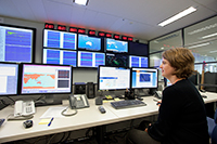 Seismologist sitting at a desk in front of a bank of computer screens