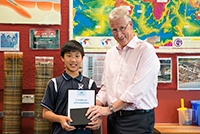 Geoscience Australia's Chief Executive Officer Dr Chris Pigram presents a certificate to a student visitor.