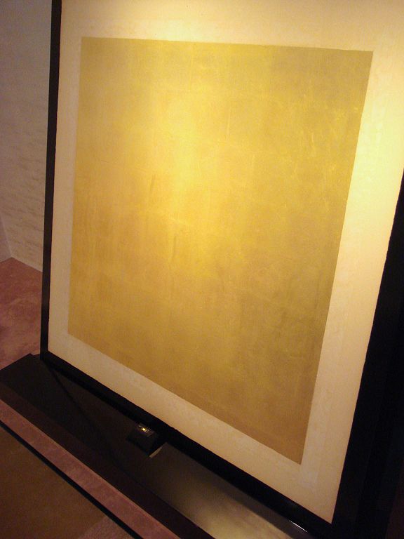 A sheet of gold foil in a frame, leaning on a wall