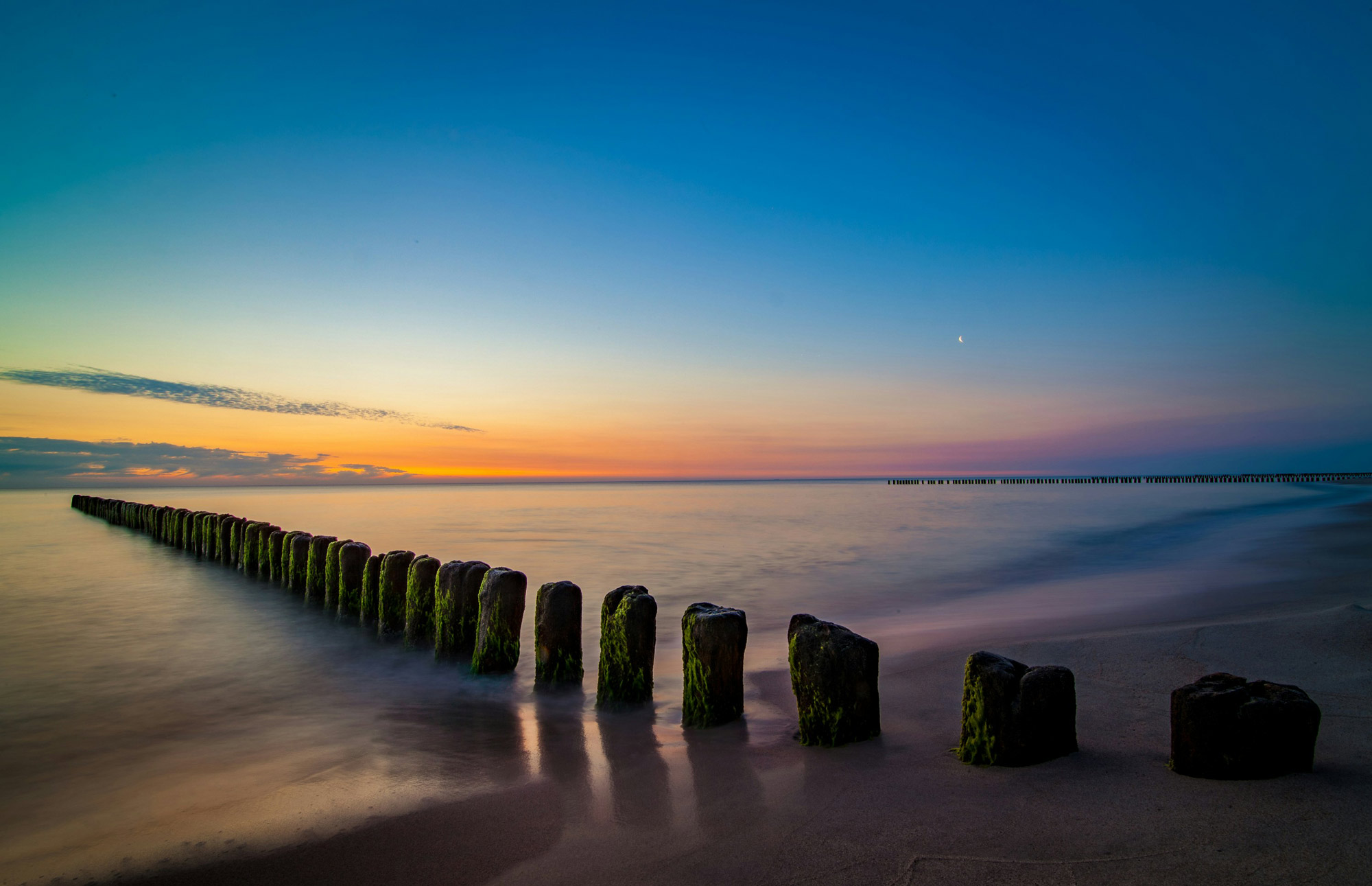Wooden groynes extending into the sea at sunset, illustrating the low-water coastline used to define Australia's maritime baselines and maritime jurisdiction