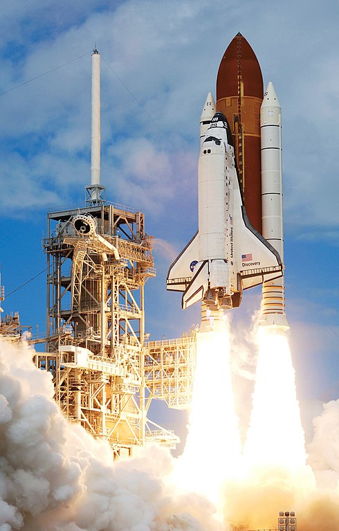 The Space Shuttle Discovery lifting off from a launch pad with flames and clouds of smoke shooting out of its base