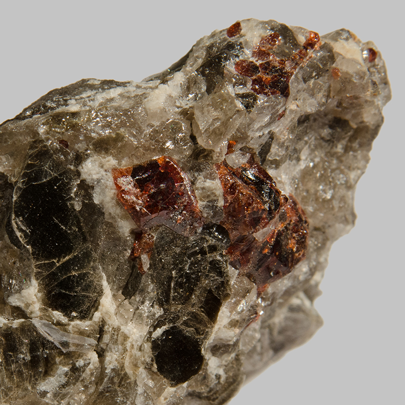 Dark and orange-red coloured crystal in a grey and white rock