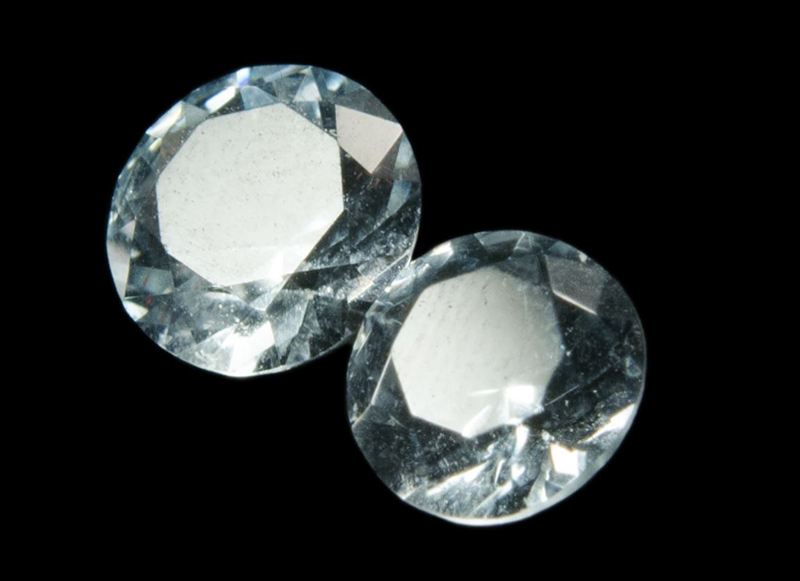 Two  sparking transparent, faceted, round topaz gemstones.