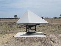A triangular shaped survey marker mounted on a concrete base in a field