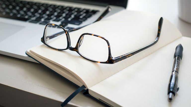 Workspace with laptop, notepad and glasses