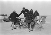 Four Antarctic expeditioners eating a meal at a picnic table