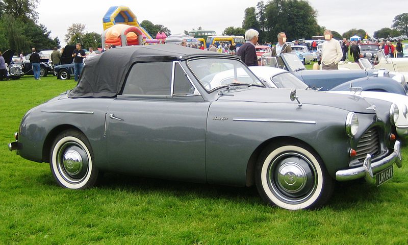 An old fashioned, silver, 1951 Austin A40 sports car with a soft black top