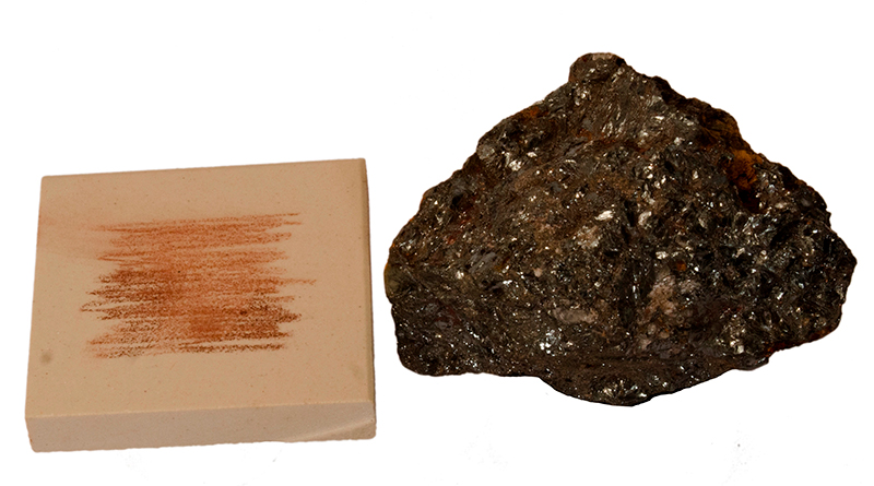 A white tile with orange streaks on it beside a rock with shiny metallic surfaces