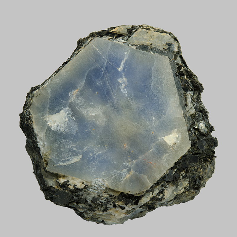 Pale blue and white, hexagonal shaped corudum crystal in a white and grey rock