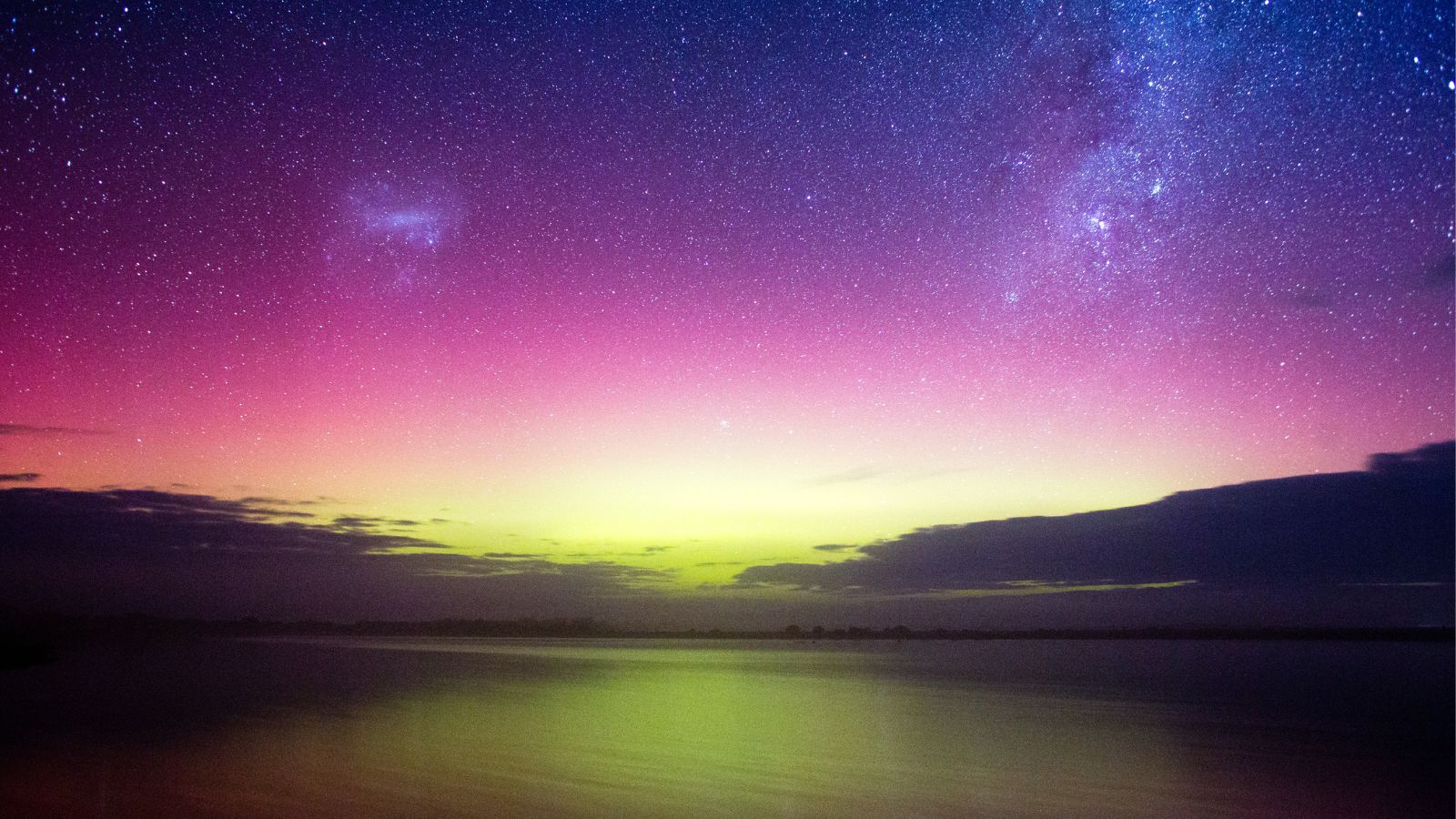 Night time landscape with the sky lit up in shades of pink and purple from the Aurora Australis