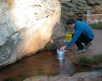 A scientist using gas monitoring equipment to measure carbon dioxide (CO2) levels from a stream that contains a naturally occurring CO2 seep