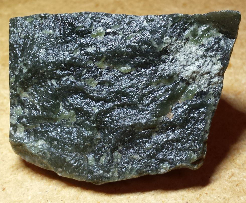 Dark coloured rock with light coloured glassy parts.