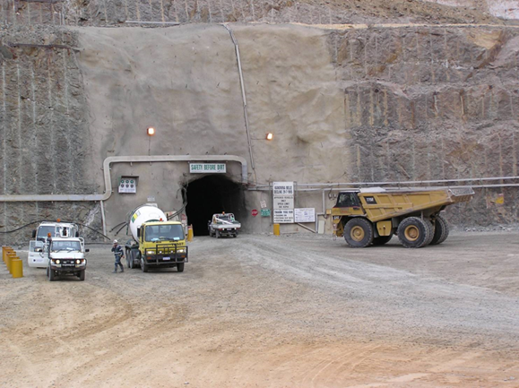 Mining vehicles and a large mining truck in front of an underground mine entrance portal