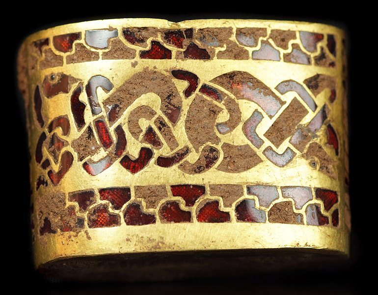 Gold coloured metal sword fitting with many red garnets embedded in it.