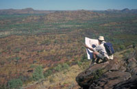 A man sitting on a rock reading a map.