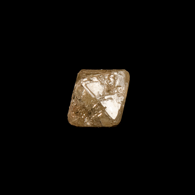 Pale yellow, partially transparent, diamond crystal with rounded corners
