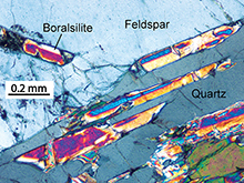 A brightly coloured microscopic image of the rare mineral boralsilite