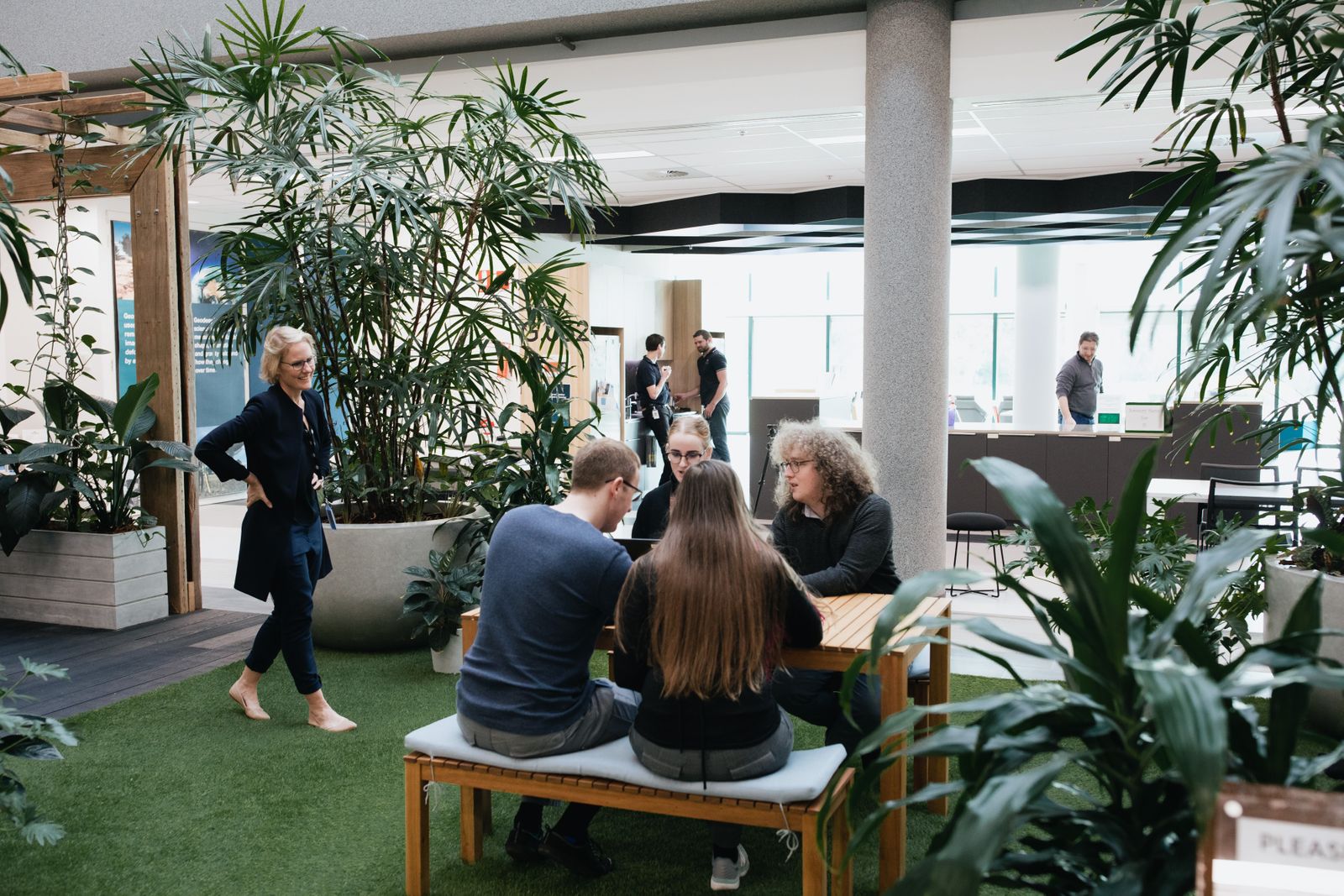 Staff talking in an office space and looking at a laptop