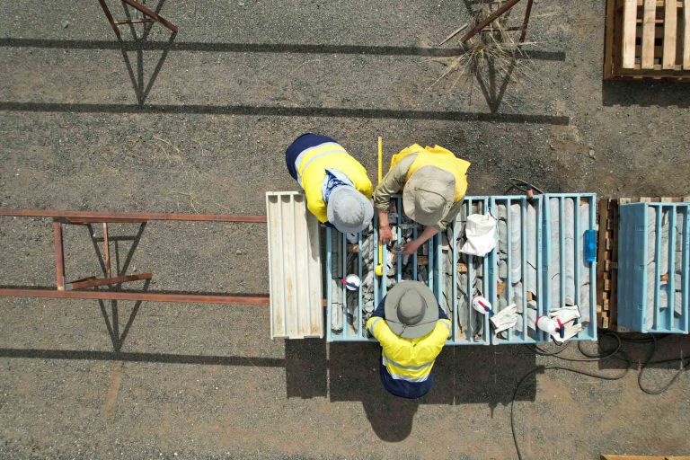 Overhead image of geologists assessing drill core in a drill tray.