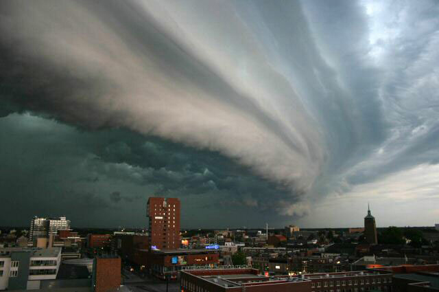 A large dark storm cell and clouds sitting over a city.