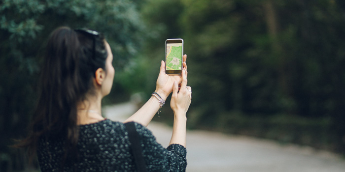 A lady holding a mobile device showing a map on screen