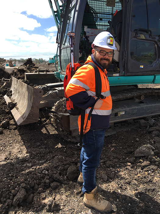 Construction worker standing in front of an excavator