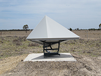 A triangular shaped survey marker mounted on a concrete base in a field