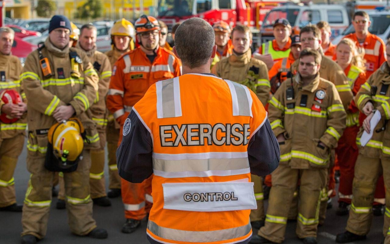 A man wearing a high vis vest talking to a group of emergency workers