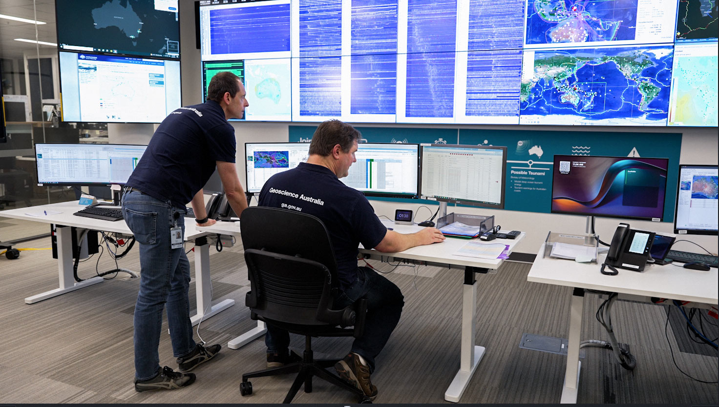 In Geoscience Australia’s National Earthquake Alerts Centre, two seismologists look at screens showing seismic activity