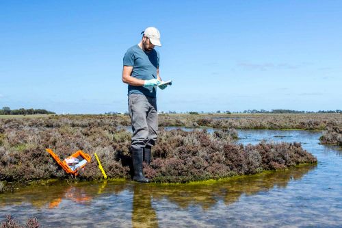 Man sampling water with notebook and equipment on lake